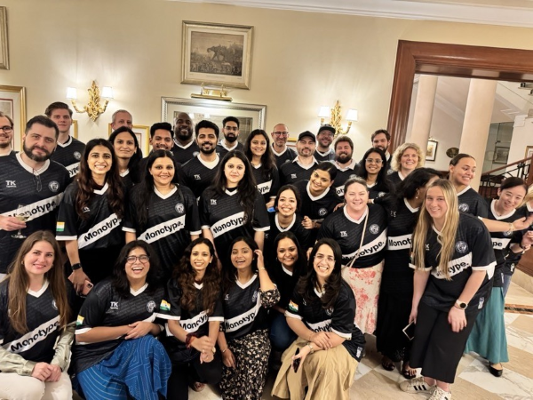 The legal team at their 2024 summit in India. Large group shot of about 20 people in black Monotype shirts.